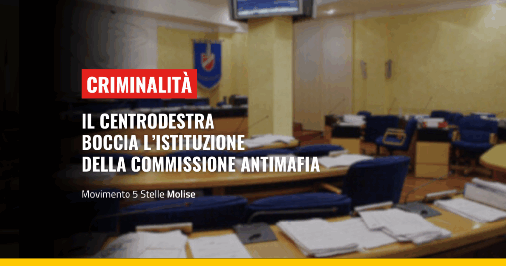 Una sala riunioni politica con sedie e tavoli, su uno sfondo giallo scuro. In evidenza un banner rosso con la scritta 'CRIMINALITÀ' e un titolo bianco 'IL CENTRODESTRA BOCCIA L'ISTITUZIONE DELLA COMMISSIONE ANTIMAFIA'. Sotto, un sottotitolo 'Movimento 5 Stelle Molise'.